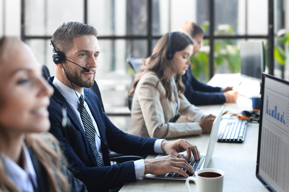 Equipo de ejecutivos de soporte con audífonos atendiendo clientes en sus computadores